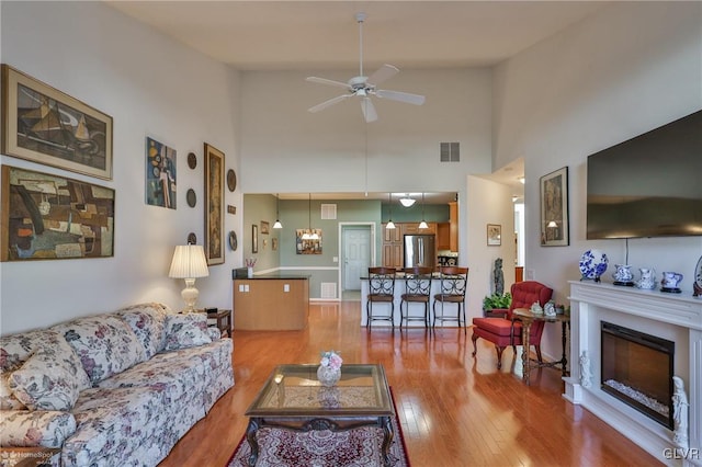 living room featuring light wood-type flooring, high vaulted ceiling, and ceiling fan