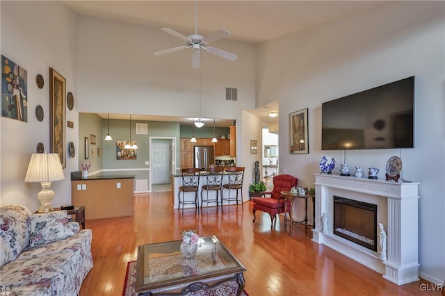 living room featuring ceiling fan, light hardwood / wood-style flooring, and high vaulted ceiling