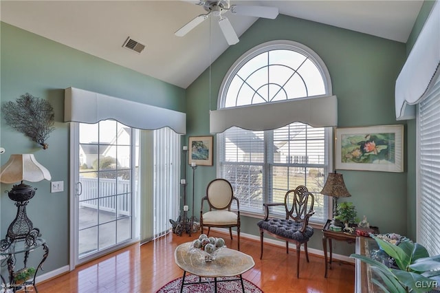 living area with ceiling fan, hardwood / wood-style floors, and vaulted ceiling