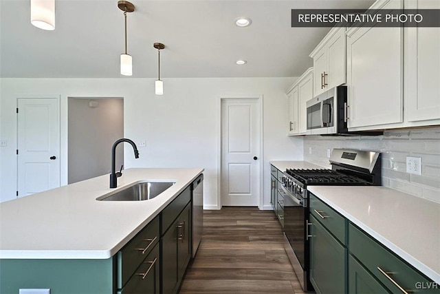 kitchen with a center island with sink, sink, appliances with stainless steel finishes, decorative light fixtures, and white cabinetry