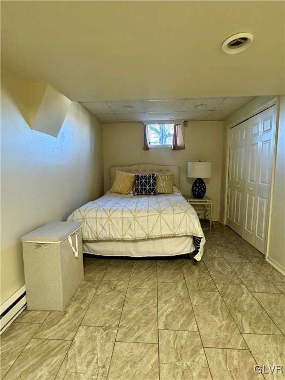 bedroom with a baseboard radiator and a drop ceiling