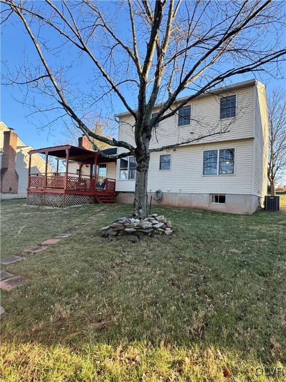 rear view of property with a wooden deck, central air condition unit, and a lawn