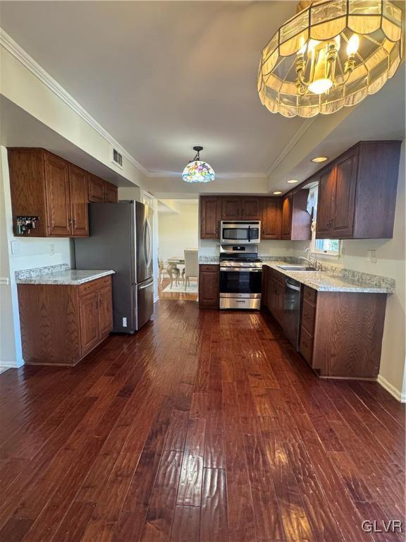 kitchen featuring hanging light fixtures, crown molding, dark hardwood / wood-style floors, and appliances with stainless steel finishes