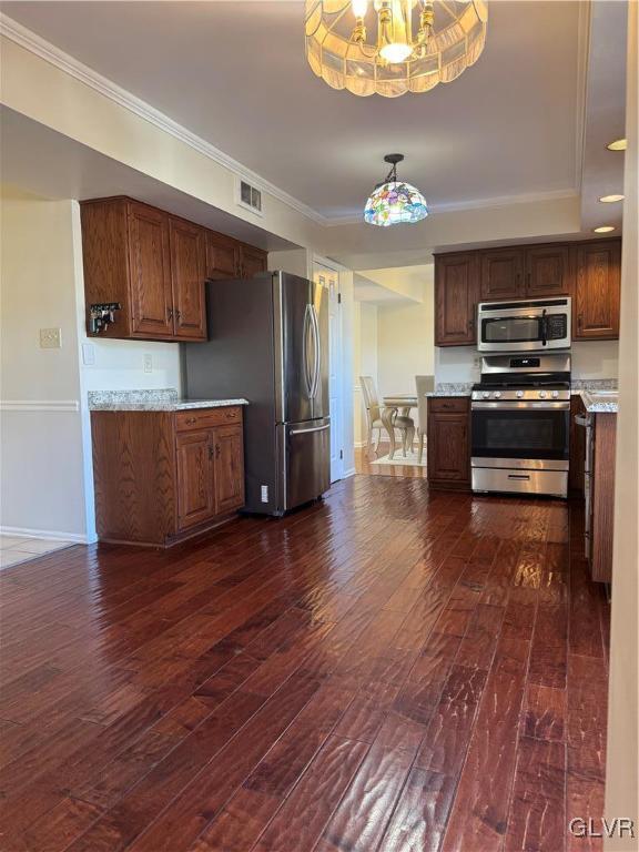 kitchen with stainless steel appliances, crown molding, dark wood-type flooring, and a notable chandelier