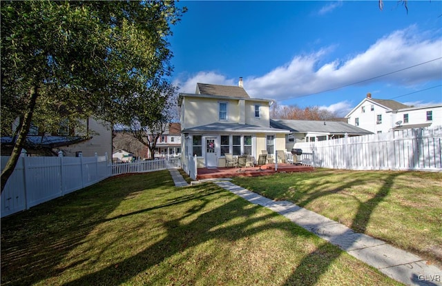 rear view of house featuring a lawn and a wooden deck