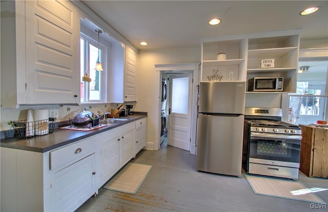 kitchen with sink, light hardwood / wood-style flooring, washer / dryer, white cabinetry, and stainless steel appliances