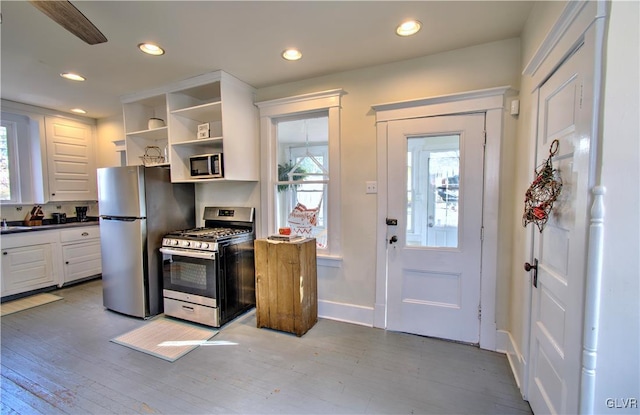 kitchen with white cabinets, light wood-type flooring, stainless steel appliances, and ceiling fan