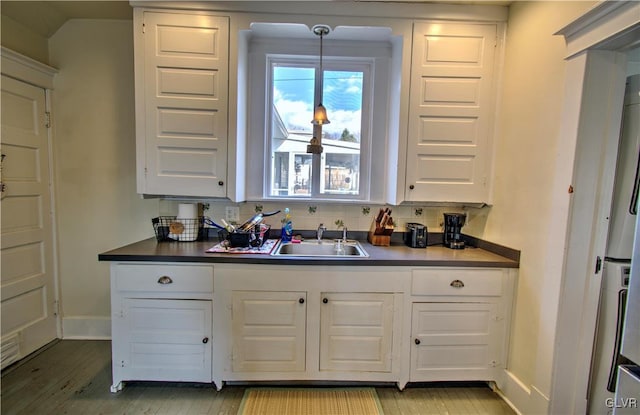 kitchen featuring sink, hanging light fixtures, decorative backsplash, white cabinets, and light wood-type flooring