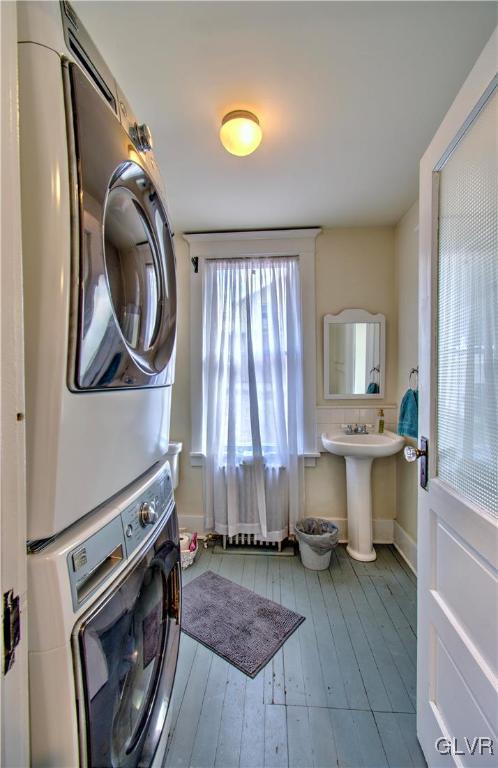 laundry area with stacked washer / dryer and sink