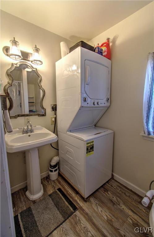 washroom featuring dark wood-type flooring and stacked washer and clothes dryer