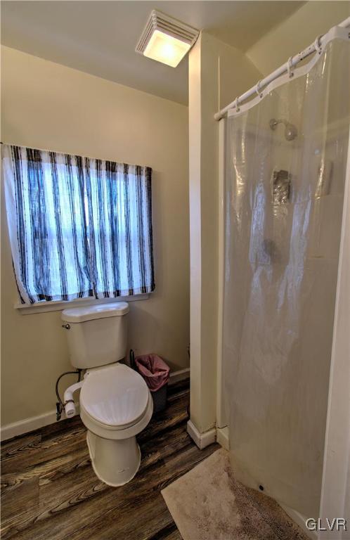 bathroom featuring hardwood / wood-style flooring, curtained shower, and toilet