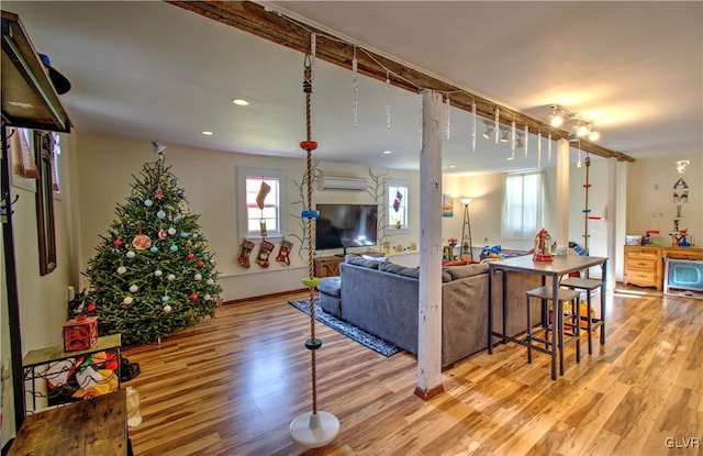 living room with a wall mounted air conditioner and light wood-type flooring