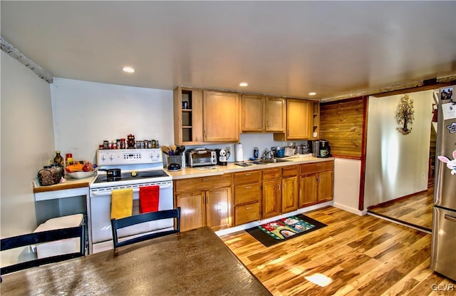 kitchen featuring light hardwood / wood-style floors, electric stove, sink, and stainless steel refrigerator