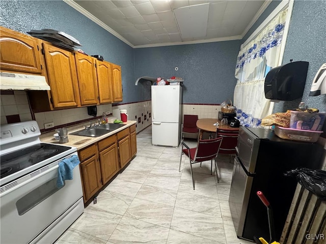 kitchen with white appliances, crown molding, and sink