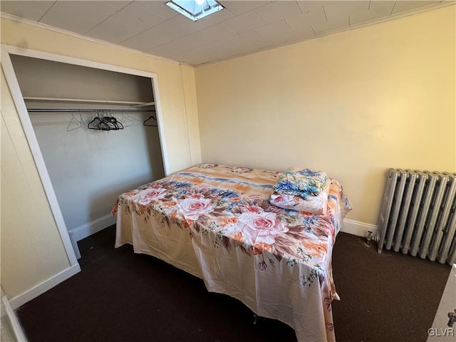 bedroom with a closet, radiator heating unit, and dark colored carpet