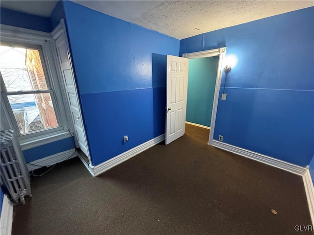 unfurnished bedroom featuring dark carpet and a textured ceiling