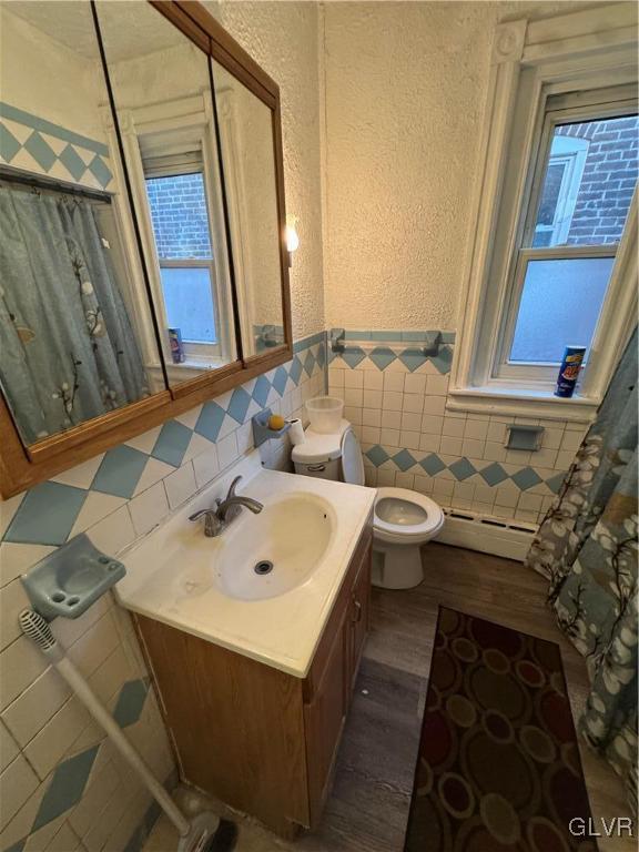 bathroom with vanity, a healthy amount of sunlight, wood-type flooring, and a baseboard heating unit