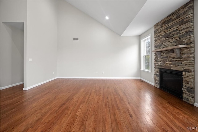 unfurnished living room with dark hardwood / wood-style flooring, a stone fireplace, and lofted ceiling