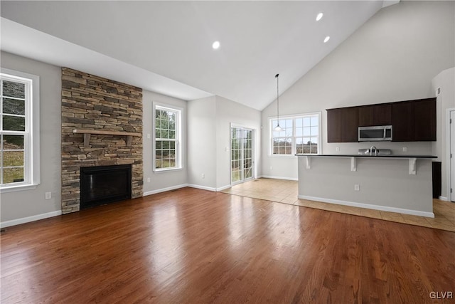 unfurnished living room featuring a wealth of natural light, light hardwood / wood-style flooring, and high vaulted ceiling