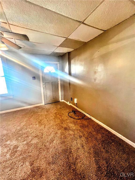 basement with a paneled ceiling and carpet floors