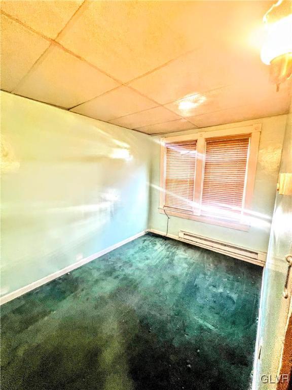 spare room featuring carpet flooring and a baseboard heating unit