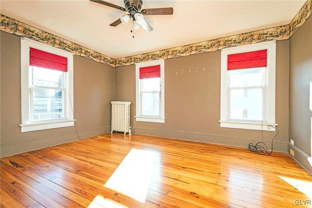 empty room featuring hardwood / wood-style flooring, a healthy amount of sunlight, and radiator