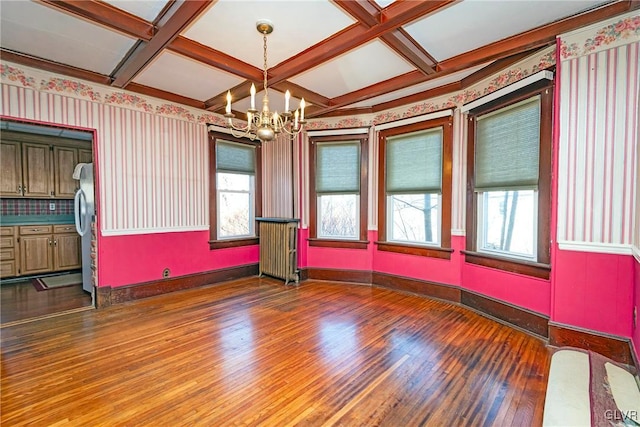 empty room with beam ceiling, radiator heating unit, coffered ceiling, an inviting chandelier, and hardwood / wood-style flooring