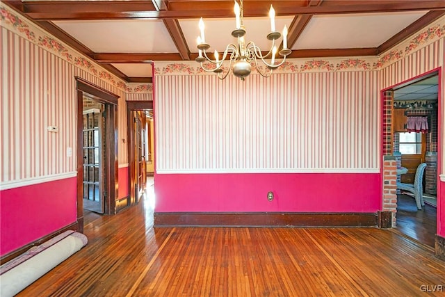 spare room featuring beam ceiling, wood-type flooring, coffered ceiling, and a notable chandelier