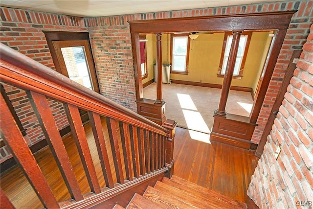 stairway with wood-type flooring and brick wall