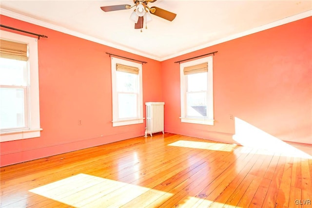 spare room featuring wood-type flooring, radiator, and crown molding