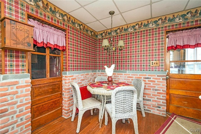 dining space featuring a drop ceiling and wood-type flooring