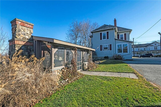 exterior space featuring a sunroom and a lawn