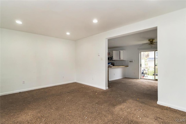 unfurnished living room with ceiling fan and dark colored carpet