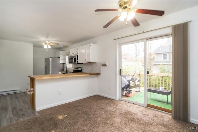 kitchen featuring kitchen peninsula, appliances with stainless steel finishes, baseboard heating, carpet floors, and white cabinetry