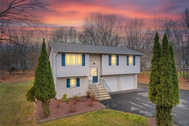 split foyer home with a garage and a lawn