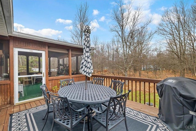 wooden deck featuring a sunroom and a grill