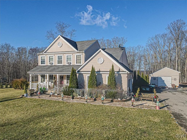 view of front of home with covered porch, a garage, an outbuilding, and a front lawn