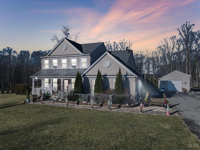 view of front of property with a lawn, an outbuilding, covered porch, and a garage