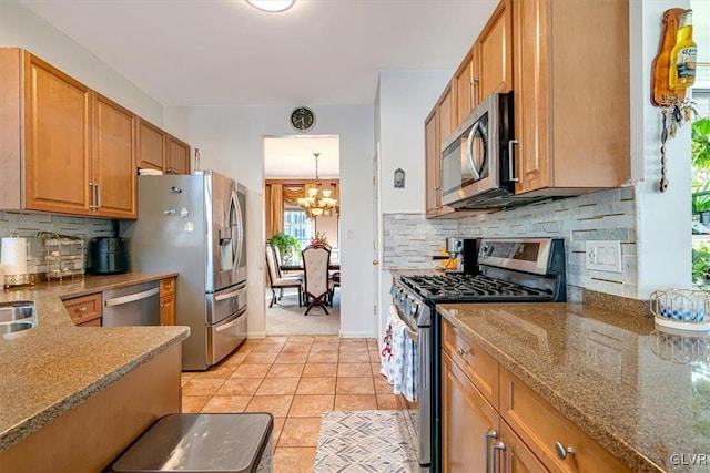 kitchen with backsplash, stainless steel appliances, light tile patterned floors, a notable chandelier, and hanging light fixtures