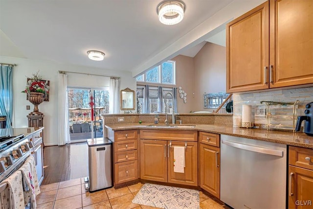 kitchen featuring sink, light tile patterned floors, appliances with stainless steel finishes, light stone counters, and kitchen peninsula