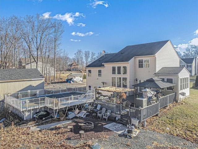 back of property featuring a deck and an outdoor fire pit