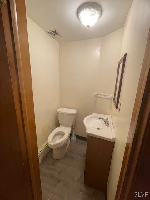 bathroom with hardwood / wood-style floors, vanity, and toilet