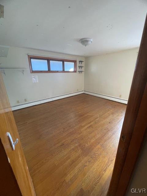 unfurnished room featuring a baseboard radiator and hardwood / wood-style flooring