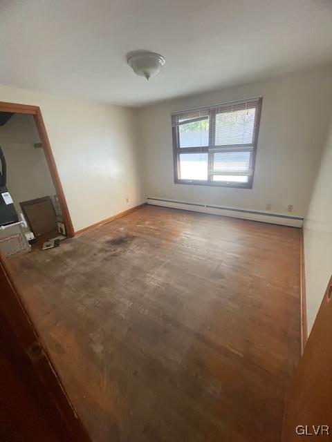 spare room featuring wood-type flooring and a baseboard heating unit