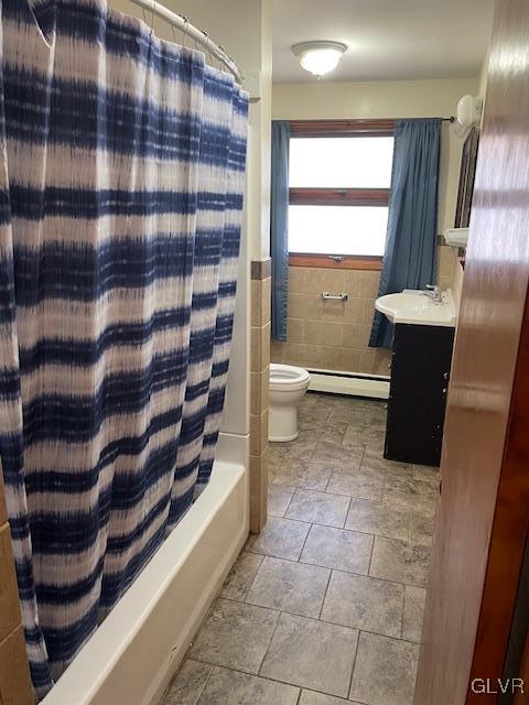 full bathroom with vanity, shower / tub combo with curtain, a baseboard heating unit, tile walls, and toilet