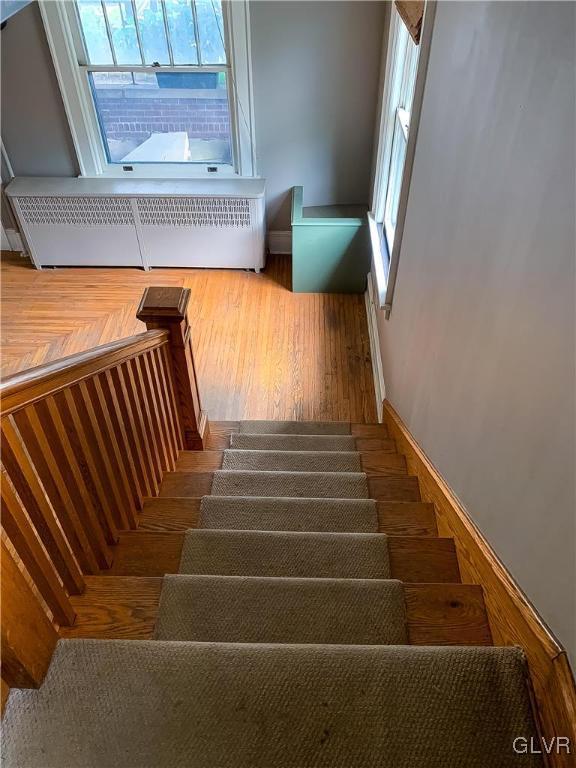 stairway featuring radiator and wood-type flooring