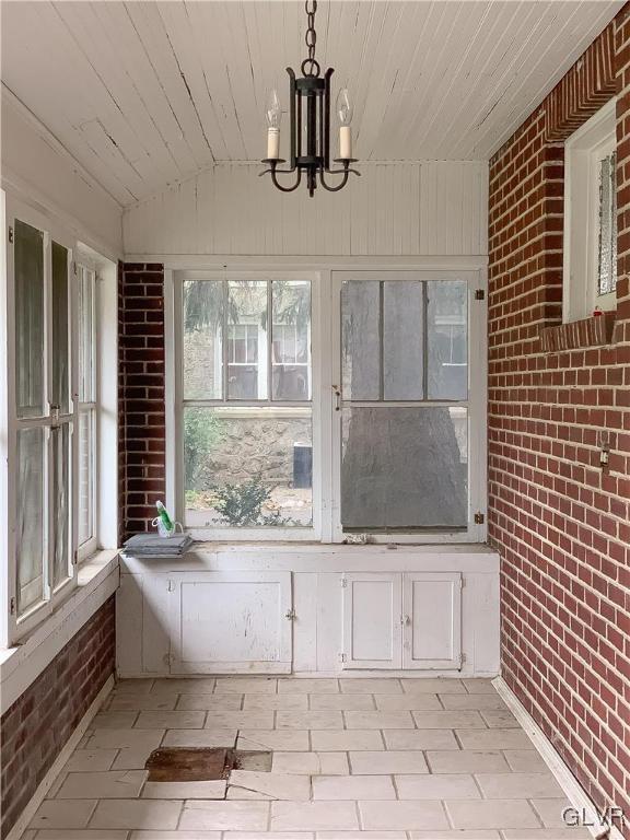 unfurnished sunroom with lofted ceiling, wooden ceiling, and a notable chandelier