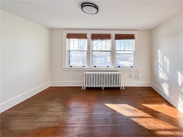 unfurnished room with dark hardwood / wood-style floors and radiator