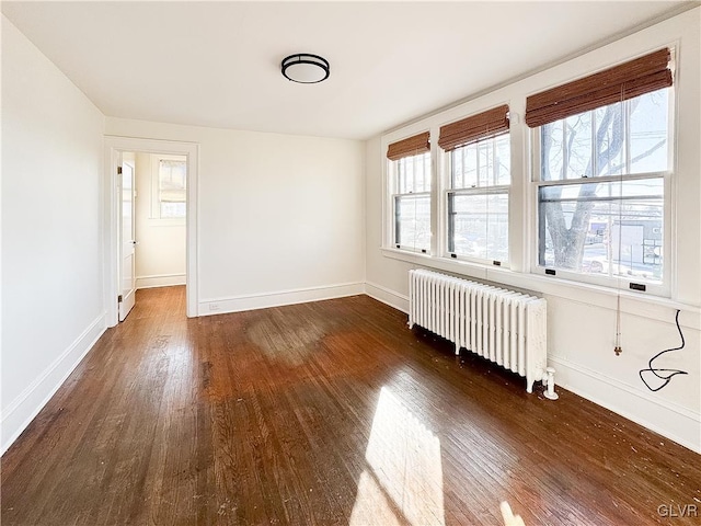 spare room featuring dark hardwood / wood-style floors and radiator