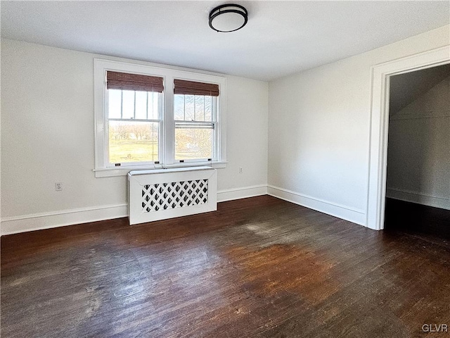 empty room with dark hardwood / wood-style flooring and radiator